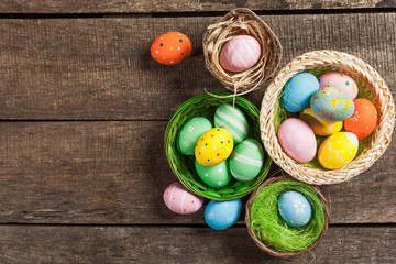 Easter eggs in nest on color wooden background
