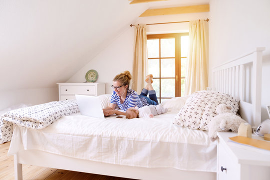 Mother with baby at home working with laptop
