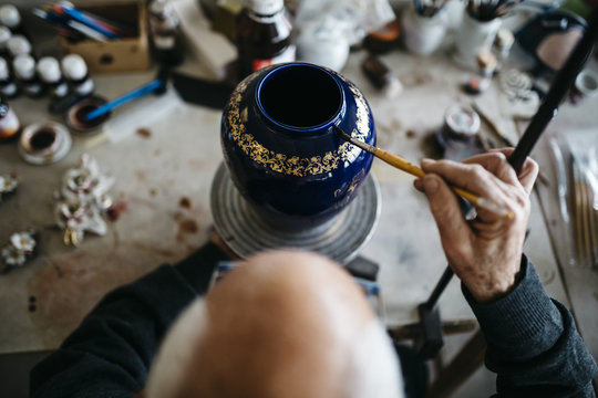 Senior man decorating ceramic vase in his spare time