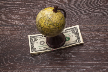 Globe and money on a background of a wooden cover.