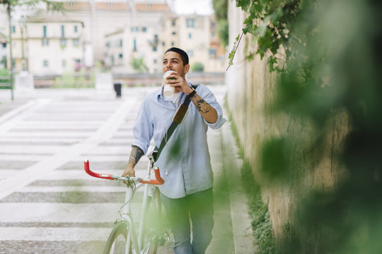 Young man walking with a bicycle in the city