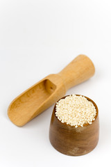 Wooden measuring spoon with bowl full of sesame