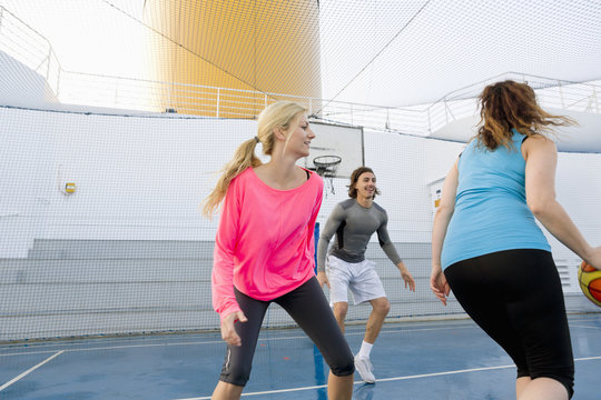 Three people playing basketball on a deck of a cruise ship