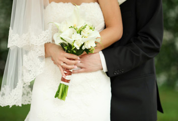 Bride and groom holding bridal bouquet close up