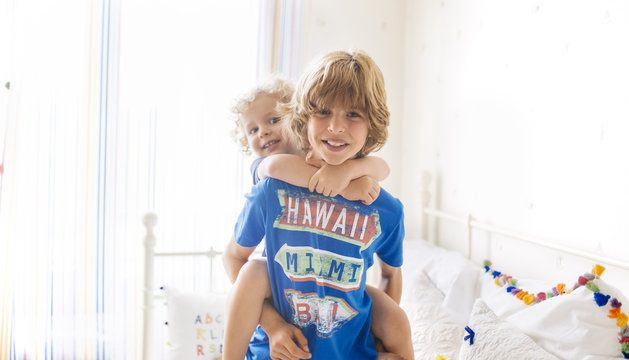 Boy giving his little brother a piggyback ride at home