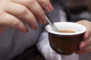 Woman Stirring a Coffee with a Spoon