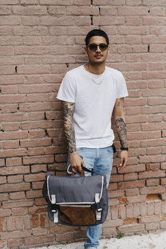 Young man leaning against a brick wall