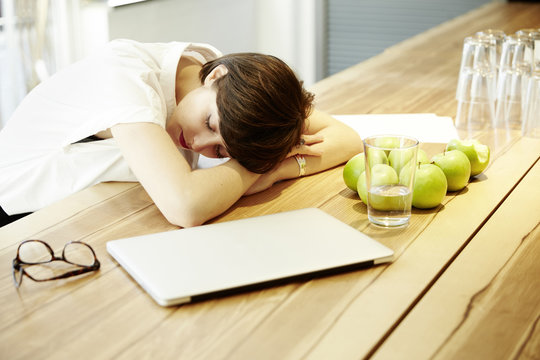Woman napping at table in canteen of a modern office