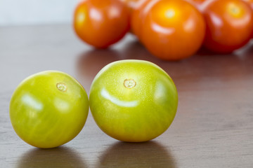 Raw tomato with ripe tomato background on wooden table.