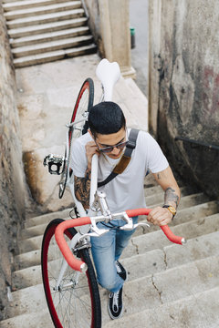 Young man carrying a bicycle on stairs