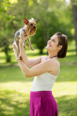 woman beautiful young happy holding small dog in summer day walks in park
