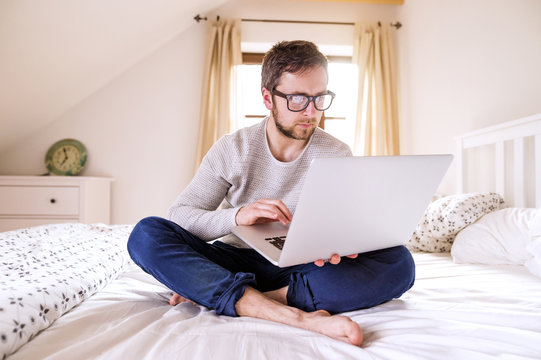 Man sitting on bed using laptop