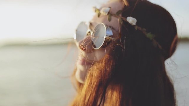 Portrait of a beautiful hippie girl in boho style fashion in a beach at sunset