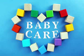 Colorful cubes in heart shape on blue background. Baby care concept