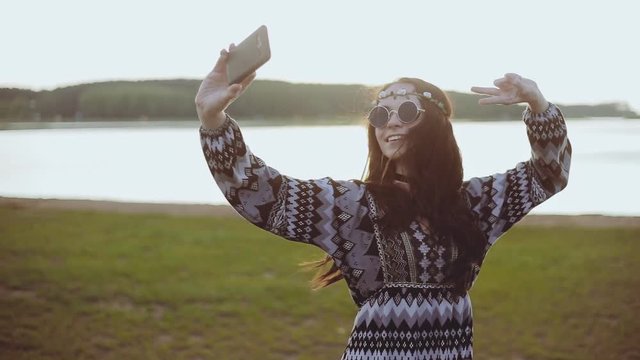 Smiling teenage girl dressed in boho style doing selfie phone