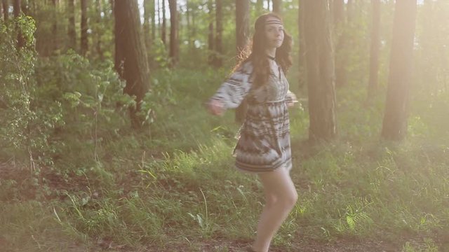 Stylish beautiful girl dressed in boho style revolves around you in the wild forest. Sun and rain