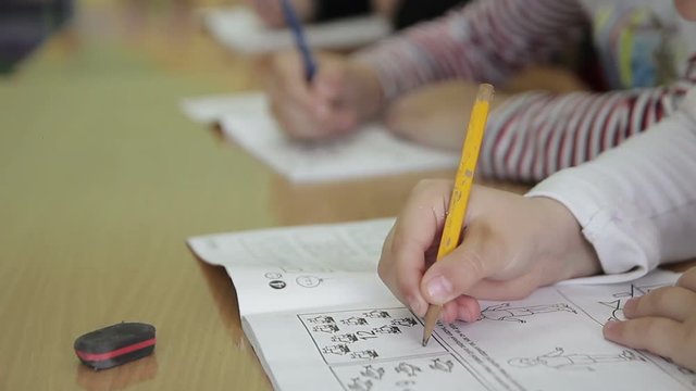children write in a notebook in a kindergarten class in kindergarten and school
