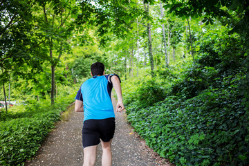 Healthy running runner man back workout in a city park. Jogging male fitness model working out training  in a park road.