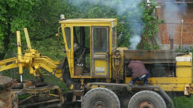 VINNITSA, UKRAINE - MAY 2016: Man starts the yellow construction bulldozer parking on road construction site