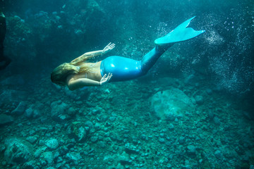 Naklejka na ściany i meble Underwater photo of a human diving in blue sea water