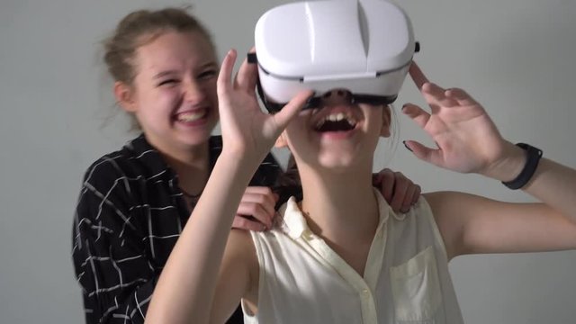 Two young and laughing teenagers playing with virtual reality headset. One of them wearing off-the-shelf VR camera