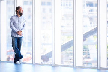 Full body shot of man with beard looking out window