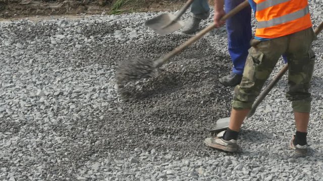 Construction workers digging gravel with shovel