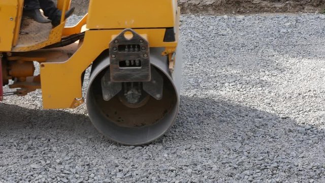 Roller compacting gravel during preparation road surface before laying an asphalt driveway