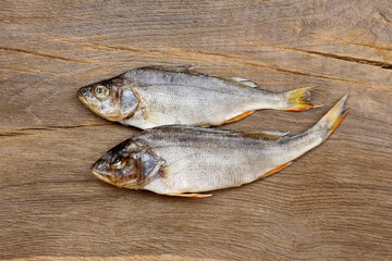 Two dried fishes on a wooden table.