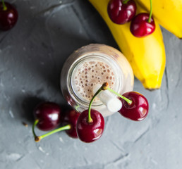 Banana smoothie with cherry in glass bottle