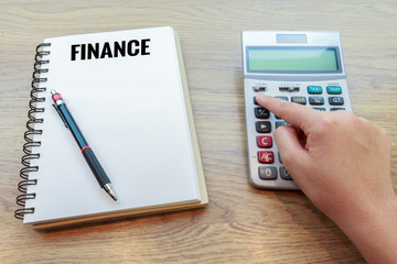 Woman hand pressing calculator button with pencil and notebook