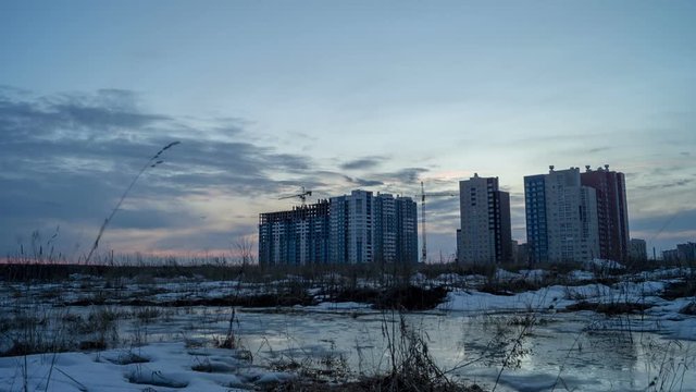 Three modern building during construction in the field at sunset, timelapse
