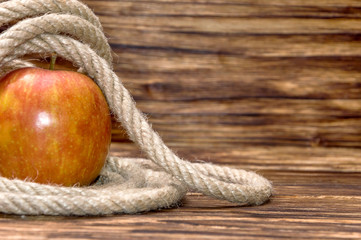 Apple with rope on wooden background