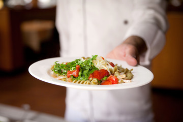 pasta with tomato sauce, cheese and greens on a plate that holds the waiter