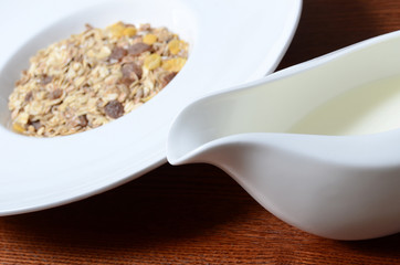 Healthy breakfast background. Bowl of corn flakes with jar of milk on wooden table