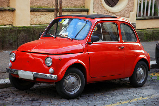 funny red small old little italian car with round headlights and