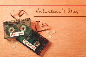 Retro audio cassettes with tapes in shape of hearts on pink textured background