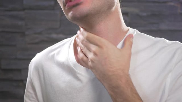 Man showing throat pain by holding his neck.