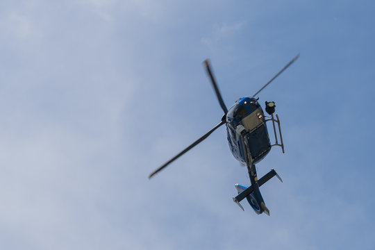 Police helicopter on blue sky flying and searching criminals.