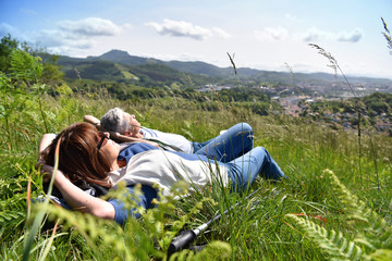 Senior couple relaxing in field on hiking day