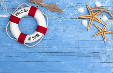 Maritime Dekoration auf blauem Holzhintergrund mit Holzschiff, Seestern, Muscheln, Treibholz ud Fischernetz 