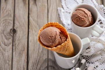 Chocolate ice cream in waffle cone on rustic wooden background, selective focus, copy space