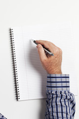 top view of a human hand writing on book.