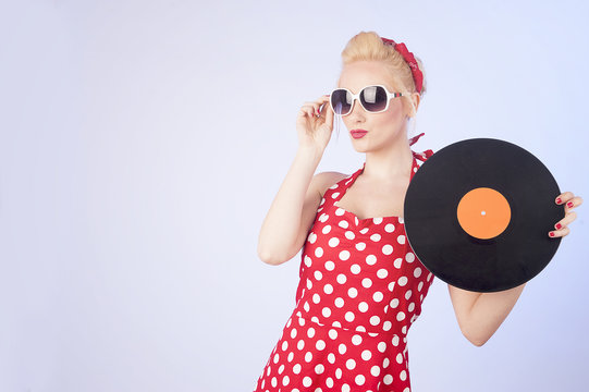 Pin-up girl in vintage dress holding a vinyl record 