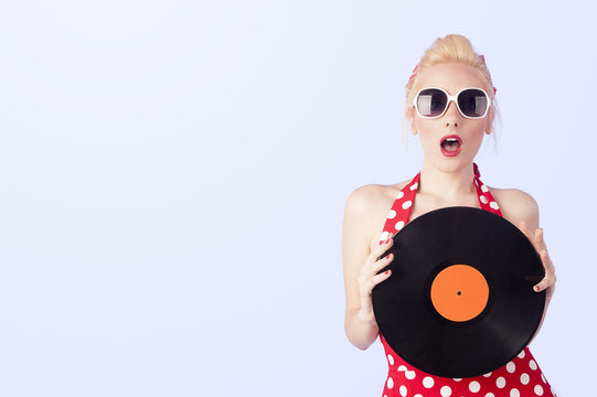 Pin-up girl in vintage dress holding a vinyl record 