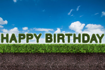 happy birthday text on green grass with soil on blue sky.