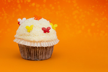 cupcake mit orangem bokeh Hintergrund und bunten Schmetterlingen