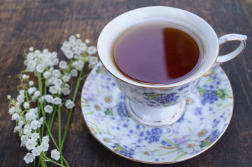 Bouquet of flowers and cup of tea on a wooden table