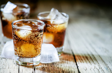 Rum and cola and ice, dark wood background, selective focus, sha