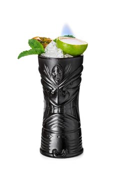 Black tiki mug decorated with burning sugar inside the lime sandpaper, mint leaves, crushed ice and pineapple slice 